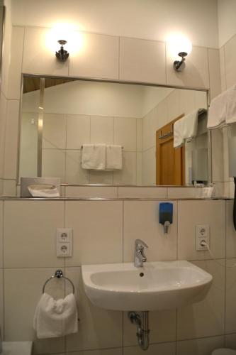 a bathroom with a sink and a mirror at Alpina Hotel in Rosenheim
