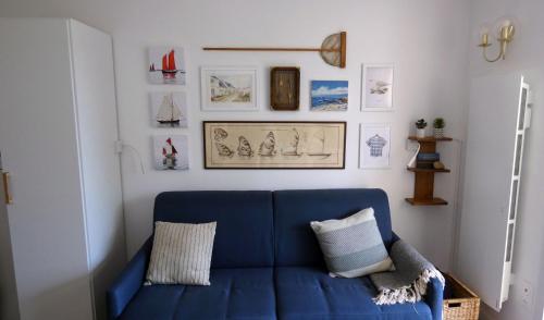 - un canapé bleu dans une chambre avec des photos sur le mur dans l'établissement Les Haubans * Moderne * Calme * Wifi, à La Trinité-sur-Mer