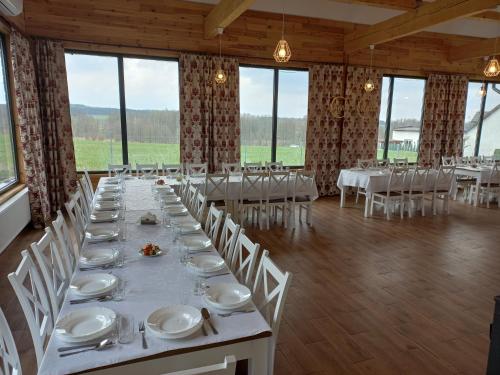 a large banquet hall with white tables and chairs at Dom Piotra in Goniadz