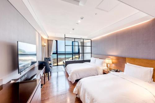 a hotel room with two beds and a flat screen tv at Dyne Oceano Hotel in Jeju