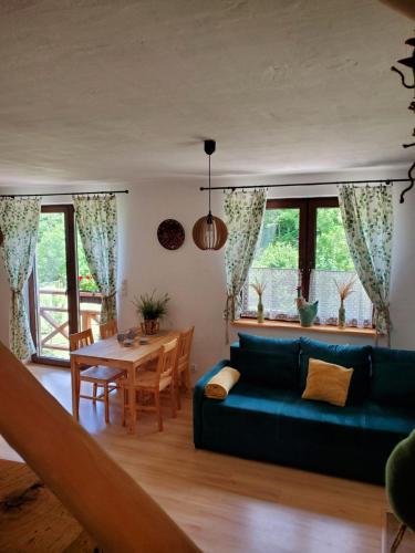 ein Wohnzimmer mit einem blauen Sofa und einem Tisch in der Unterkunft Zagroda Berezanka 600-739-125 in Polańczyk