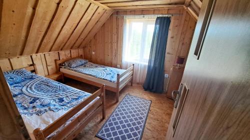 um pequeno quarto com 2 camas e uma janela em Wigierska Buchta (DOMKI) em Rosochaty Róg