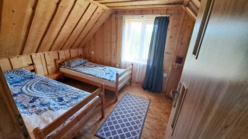 a small room with two beds and a window at Wigierska Buchta (DOMKI) in Rosochaty Róg