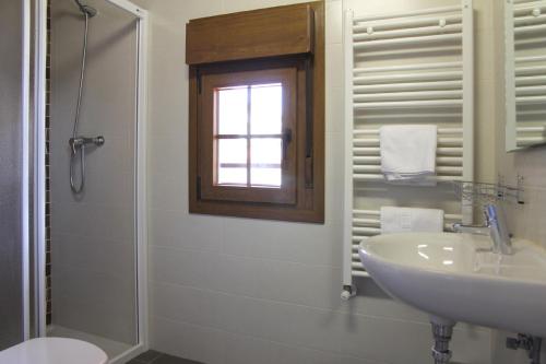 La salle de bains blanche est pourvue d'un lavabo et d'une douche. dans l'établissement Casa Rural Sarobetxea en Larrayoz, Navarra, 