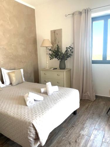 a bedroom with a bed with white sheets and a window at Hôtel Restaurant La Caravelle in Sari Solenzara