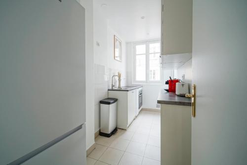 cocina blanca con fregadero y encimera en Apartment next to Palais des Congrès - Neuilly en Neuilly-sur-Seine