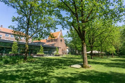 a tree in the middle of a park with a rock at Hotel Kontakt der Kontinenten in Soesterberg