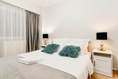 a white bed with two green pillows on it at Beautiful and cozy 2 bedroom apartment with living room loft in Cluj-Napoca