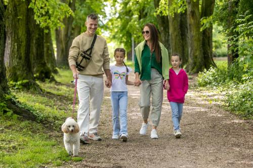 a family walking a dog on a path at Gotthard Therme Hotel & Conference in Szentgotthárd