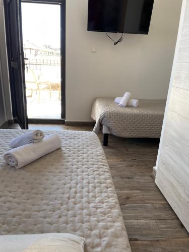 a bedroom with two beds and a television on the wall at Hôtel Restaurant La Caravelle in Sari Solenzara