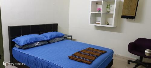 a bedroom with a bed with blue sheets and a chair at RW segamat homestay in Segamat