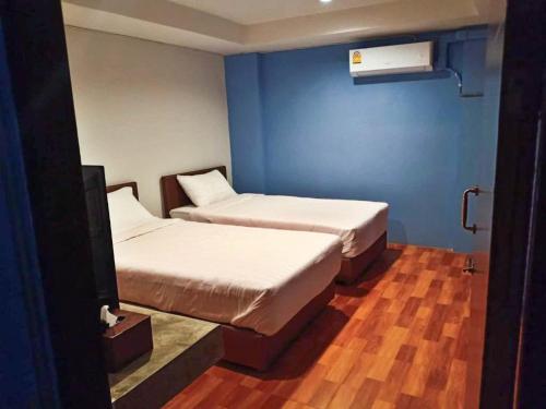two beds in a room with blue walls and wooden floors at Airport A1 Hotel in Chiang Mai