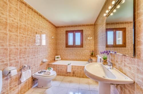 uma casa de banho com um lavatório, um WC e uma banheira em Rosas 28 em Sa Coma