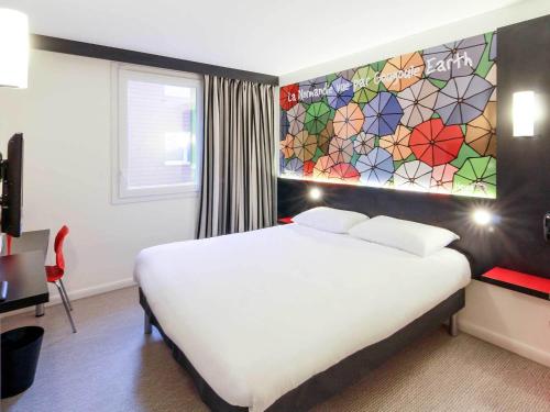 une chambre d'hôtel avec un lit et un mur en vitrail dans l'établissement ibis Styles Flers, à Flers