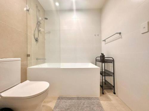 a white bathroom with a toilet and a shower at Cosy One Bedroom Apartment in Castle Hill, NSW in Castle Hill