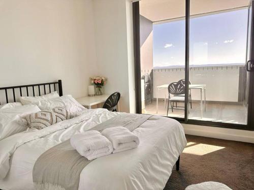 a bedroom with a white bed with two towels on it at Cosy One Bedroom Apartment in Castle Hill, NSW in Castle Hill