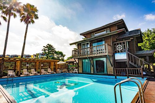 a house with a swimming pool in front of a house at Dyne Resort in Jeju