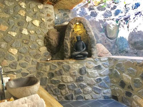 een stenen badkamer met een wastafel en een stenen muur bij Sing Sing Resort Lovina in Lovina