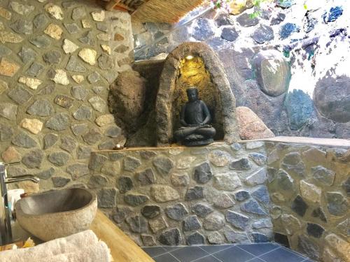 a stone bathroom with a sink and a stone wall at Sing Sing Resort Lovina in Lovina