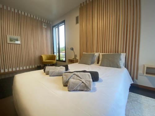 a bedroom with a large white bed with towels on it at CASA Raiz in Ponta Delgada