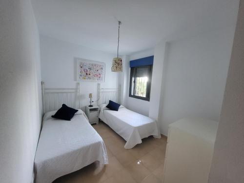 コニル・デ・ラ・フロンテーラにあるApartamento Con Jardin Y Piscinaの白い部屋で、ベッド2台、窓が備わります。