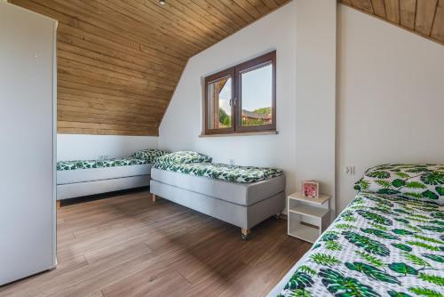 sypialnia z 2 łóżkami i drewnianym sufitem w obiekcie Domki Pieniny w mieście Grywałd