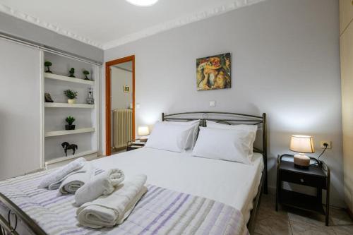 een slaapkamer met een groot wit bed en handdoeken bij Spacious Apartment with Patio in Kalamata