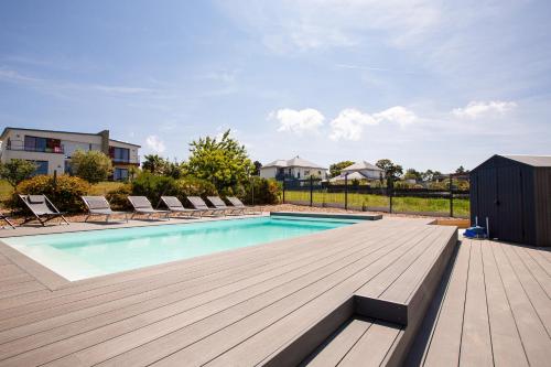 une piscine avec des chaises et une terrasse en bois dans l'établissement Villa neuve avec piscine vue sur mer pour 9, à Pléneuf-Val-André