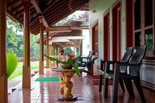 a porch with chairs and a table with a plant on it at Prakruthi Home Stay in Sollebail