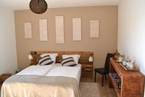 ein Schlafzimmer mit einem Bett mit zwei Kissen und einem Schreibtisch in der Unterkunft Aux Gîtes de l'Étang - Thannenkirch Bergheim in Thannenkirch