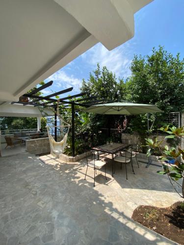 a patio with a table and chairs and an umbrella at Seaside Holiday Home Maksim in Kumbor