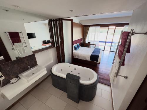 a bathroom with a bath tub and a bedroom at Samui Mekkala Resort in Choeng Mon Beach