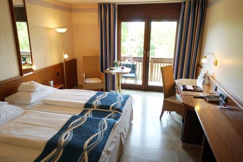 a hotel room with two beds and a desk and a window at Flair Park Hotel Ilshofen in Ilshofen