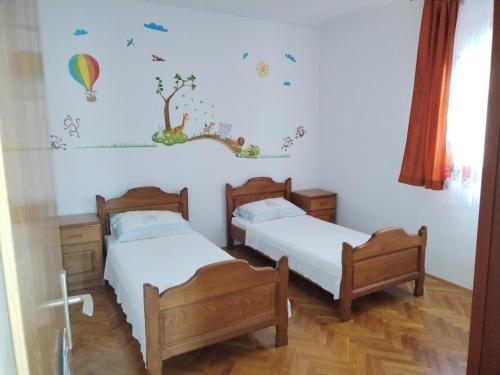 two beds in a room with white walls at Apartman Perkovic in Šibenik