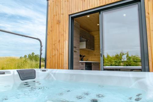 eine Badewanne in einem Zimmer mit einem großen Fenster in der Unterkunft Le Laponya - Chalet climatisé avec SPA & Borne de recharge in Bressols