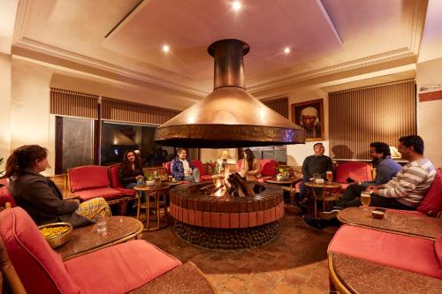 a group of people sitting in a restaurant with a fireplace at Dhulikhel Lodge Resort in Dhulikhel
