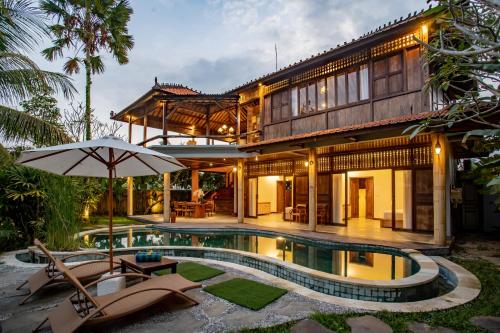 a house with a swimming pool and an umbrella at Arya Arkananta Resort & Spa in Ubud