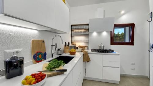 a kitchen with white cabinets and a bowl of fruit on the counter at La Maranita Apartment in La Maddalena
