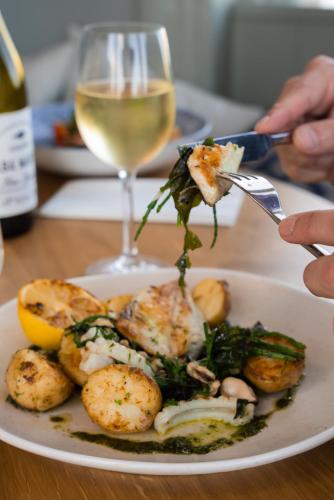 a plate of food with shrimp and vegetables and a glass of wine at Cliftonville Hotel in Cromer