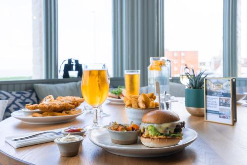 a table with plates of food and glasses of beer at Cliftonville Hotel in Cromer