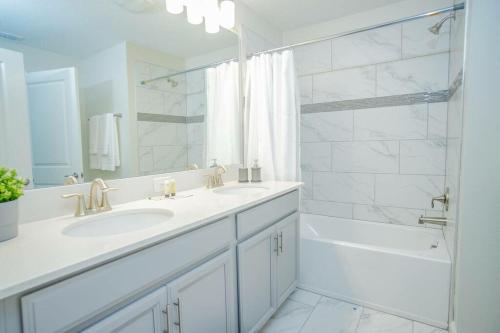 a white bathroom with two sinks and a shower at Comfy Home with Private Heated Pool BBQ Grill in Kissimmee