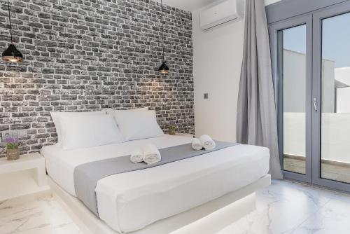 Cama blanca en habitación con pared de ladrillo en simos luxury apartments, en Naxos Chora