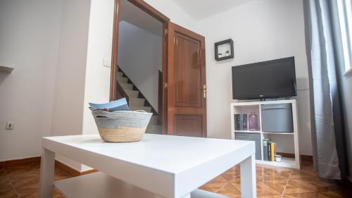 een woonkamer met een witte tafel en een tv bij La casa del muro con vistas al mar in A Guarda