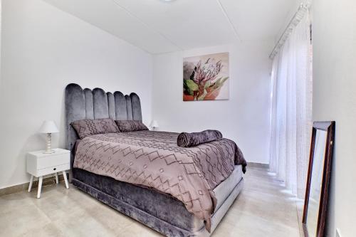een slaapkamer met een groot bed in een witte kamer bij Madison Palms apartment in Sandown in Johannesburg