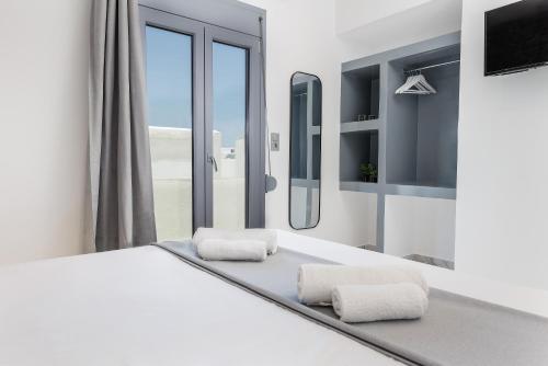 a white bedroom with a bed and a window at simos luxury apartments in Naxos Chora