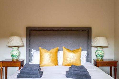 a bedroom with a bed with gold pillows and two lamps at Plaisir Estate Accommodation in Simondium