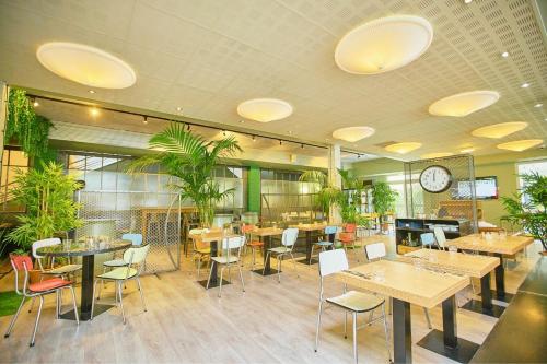 a restaurant with tables and chairs and a clock on the ceiling at Sporting House Hôtel in Toulouse