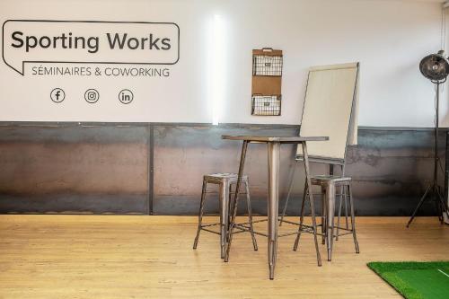 a table and stools in a room with a chalkboard at Sporting House Hôtel in Toulouse