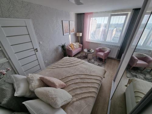 um quarto com uma cama, 2 cadeiras e uma janela em ALPHA Apartman Malacky em Malacky