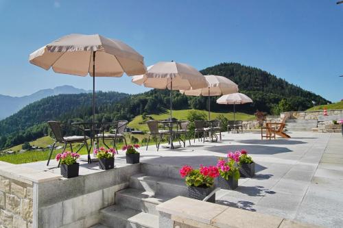 um pátio com mesas e cadeiras com guarda-sóis e flores em Villa Bello em Berchtesgaden